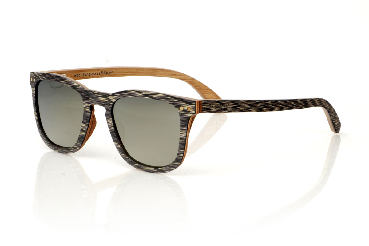 Wood eyewear of Jichimu modelo RISKY. RISKY wooden sunglasses combine a classic shape that flatters all face types with a more contained size, creating a versatile and always on-trend accessory. They are meticulously manufactured using a three-strip laminate technique: black Chicken Wing wood on the outside, maple in the center that provides luminosity, and oak on the inside, offering exceptional resistance. The temples replicate this tricolor pattern, guaranteeing coherence and style throughout the entire set. What really makes the RISKY stand out is the unique texture of its front, accented with eye-catching oak rivets. Measuring 140x47mm and a caliber of 49, these glasses are the perfect balance between comfort and style statement. | Root Sunglasses® 